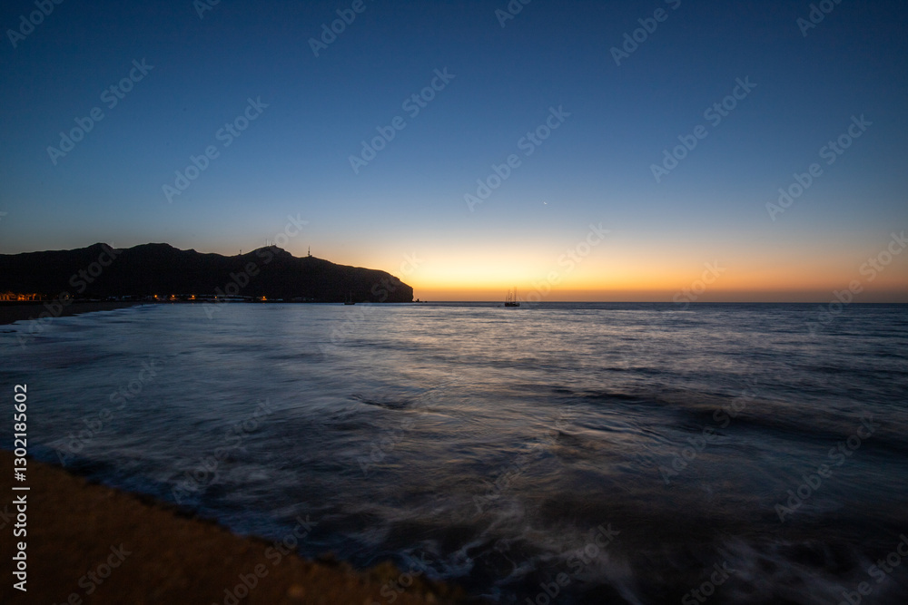 Sandy beach in the morning. Landscape shot of the sea at sunrise. Coastline of a bay, with black sand during a light sandstorm, a Calima. Gran Tarajal, Canary Islands, Spain Sandy beach in the morning. Landscape shot of the sea at sunrise. Coastline of a bay, with black sand during a light sandstorm, a Calima. Gran Tarajal, Canary Islands, Spain