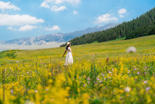 Young woman traveler relaxing and enjoying at beautiful blooming flower fields at sayram lake in Xinjiang, China
