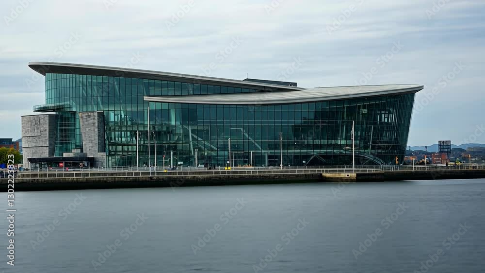 Modern architectural design of a large glass structure by the waterfront in a city during daylight Modern architectural design of a large glass structure by the waterfront in a city during daylight