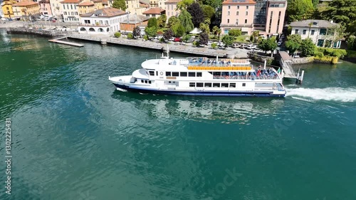 4k droone footage of a ferry boat in Lake Como, with the town of Dongo in the distance in Italy