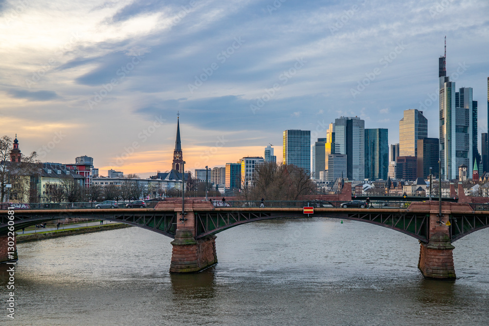 View from a Main Bridge of a skyline in the financial district in the background as the sun sets. Twilight in Frankfurt am Main, Hesse Germany View from a Main Bridge of a skyline in the financial district in the background as the sun sets. Twilight in Frankfurt am Main, Hesse Germany