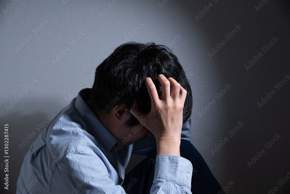 頭を抱えて悩む男性とスポットライト