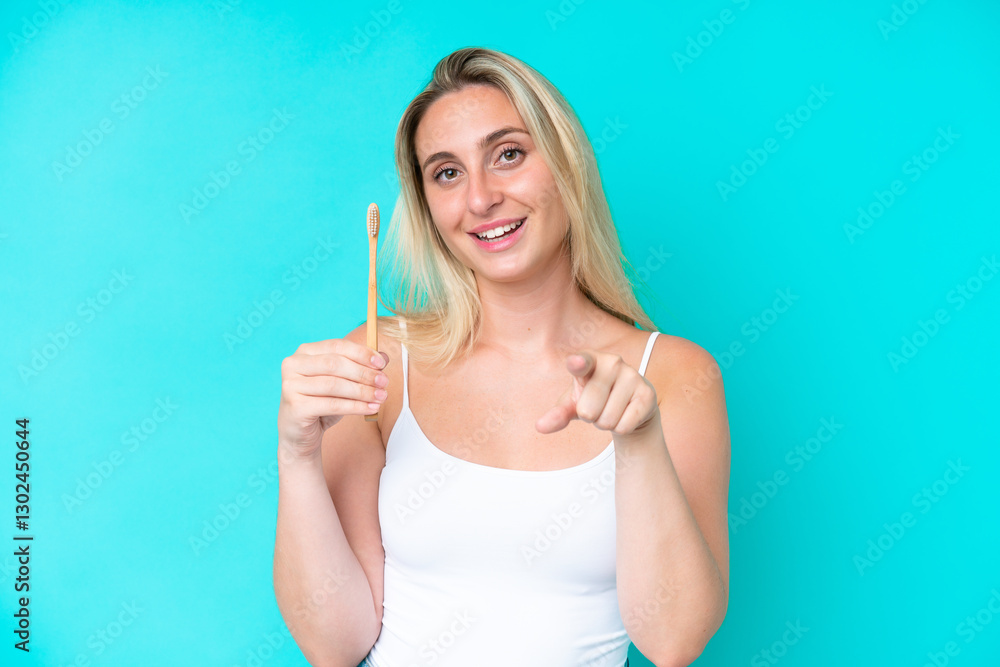 Young caucasian woman brushing teeth isolated on blue background points finger at you with a confident expression Young caucasian woman brushing teeth isolated on blue background points finger at you with a confident expression