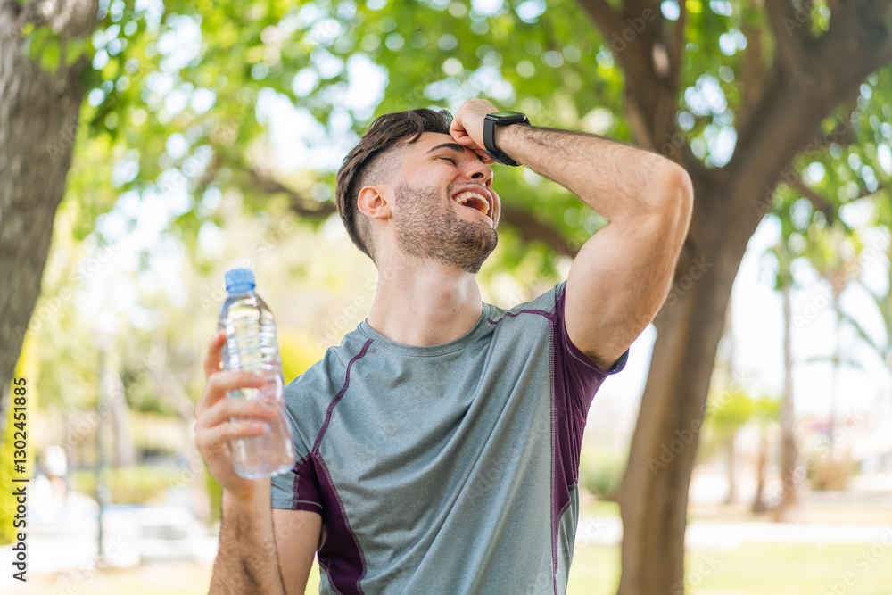 Young handsome sport man with a bottle of water at outdoors has realized something and intending the solution Young handsome sport man with a bottle of water at outdoors has realized something and intending the solution
