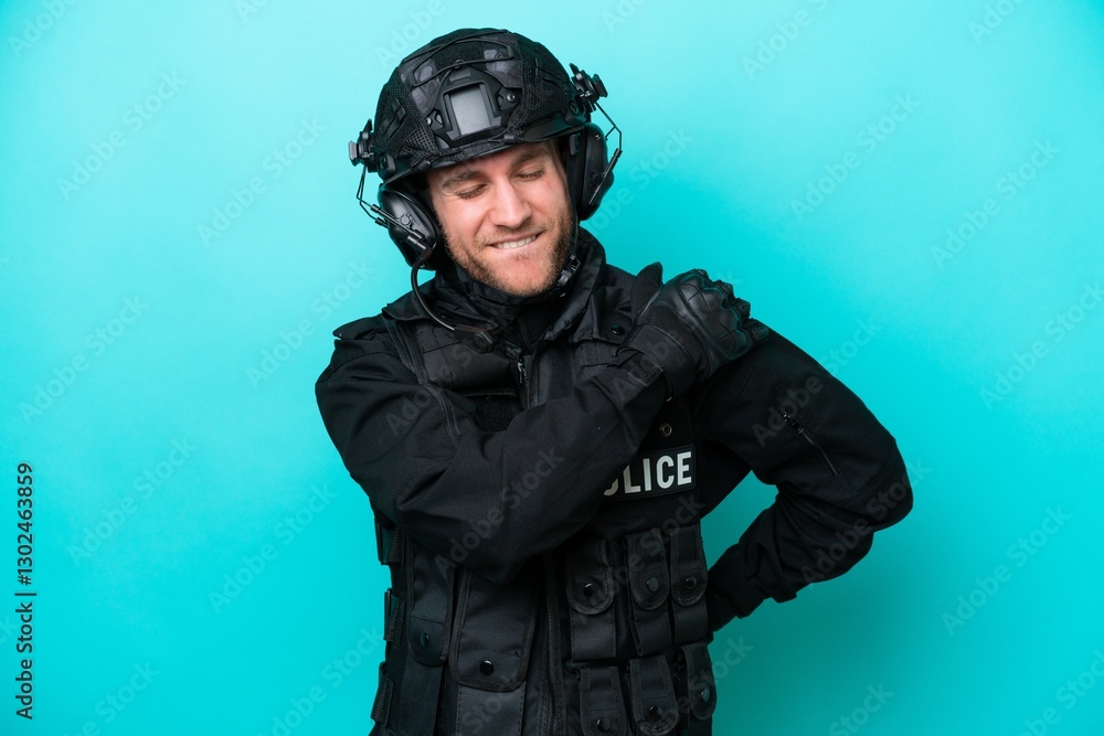 SWAT caucasian man isolated on blue background suffering from pain in shoulder for having made an effort SWAT caucasian man isolated on blue background suffering from pain in shoulder for having made an effort