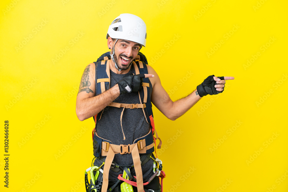 Fototapeta premium Young caucasian rock climber man isolated on yellow background surprised and pointing side