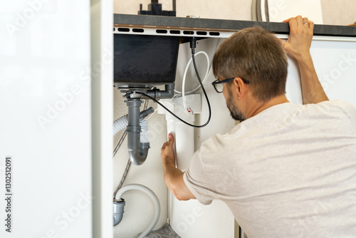 Plumber installs water filter. Replacement water purifier. Repairman changes water filter cartridges in kitchen under kitchen sink. Osmosis