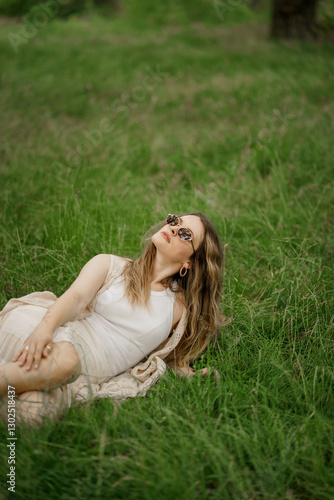 young woman lying on the grass in glasses looking up at the sky 