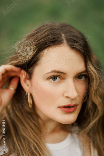 A girl holding flower in her hair, in the park during summer day 