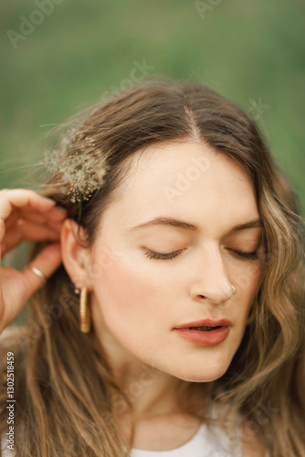 Girl holding flower in her hair looking down during summer day in the garden 