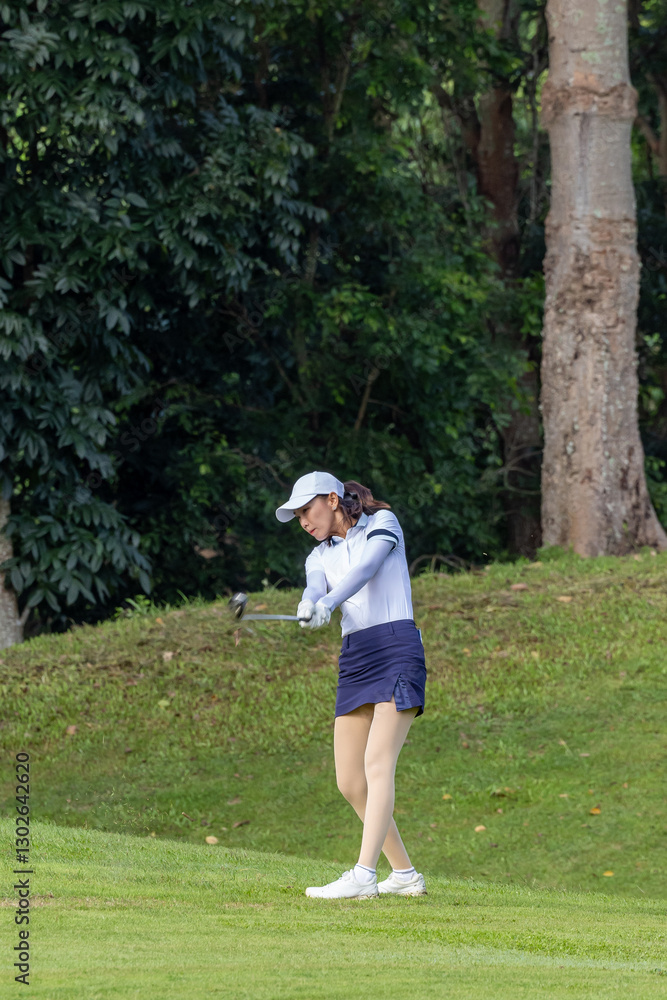 Asian woman professional golfer play golf at golf course with green golf course background, Asian woman golf player swing tee off on the green, Healthy and Lifestyle. Asian woman professional golfer play golf at golf course with green golf course background, Asian woman golf player swing tee off on the green, Healthy and Lifestyle.