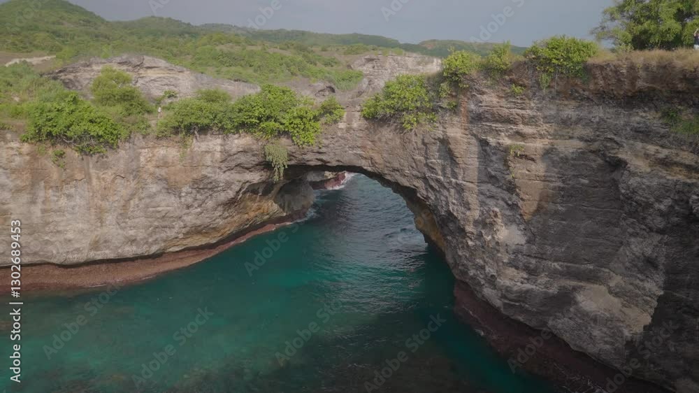 A natural archway carved into a dramatic cliff face overlooking a turquoise sea. The arch is a significant feature, spanning the width of the view. A natural archway carved into a dramatic cliff face overlooking a turquoise sea. The arch is a significant feature, spanning the width of the view.
