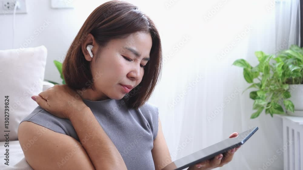 Asian woman suffering from muscle neck and shoulder pain after spending too much time overusing a tablet in poor posture Asian woman suffering from muscle neck and shoulder pain after spending too much time overusing a tablet in poor posture