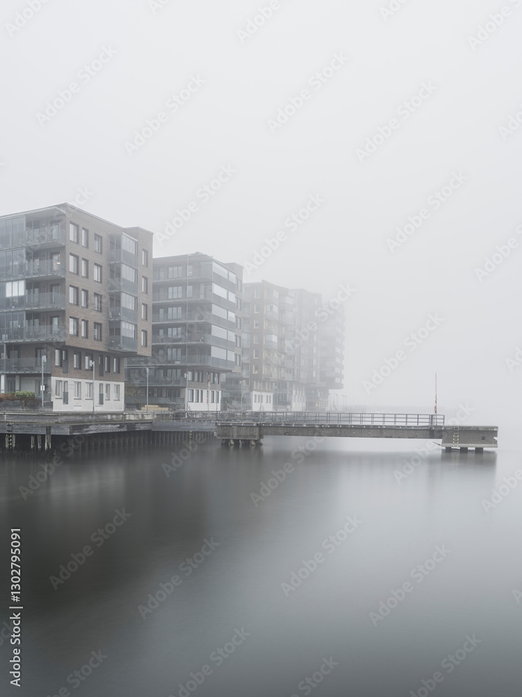 Residential buildings along the river in Gothenburg enveloped by mist during early morning hours Residential buildings along the river in Gothenburg enveloped by mist during early morning hours
