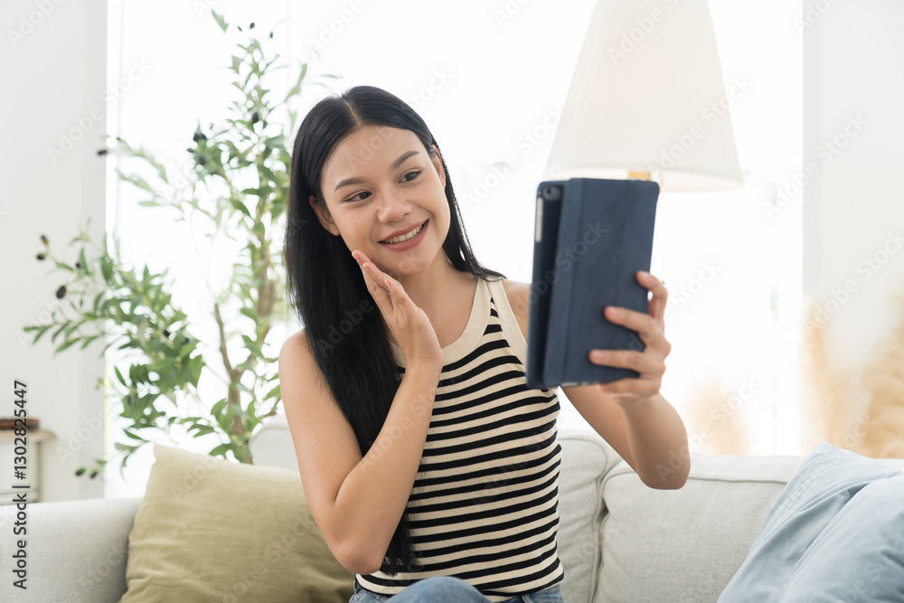 Woman, digital tablet, young asian woman using tablet during sitting on sofa in living room at home Woman, digital tablet, young asian woman using tablet during sitting on sofa in living room at home