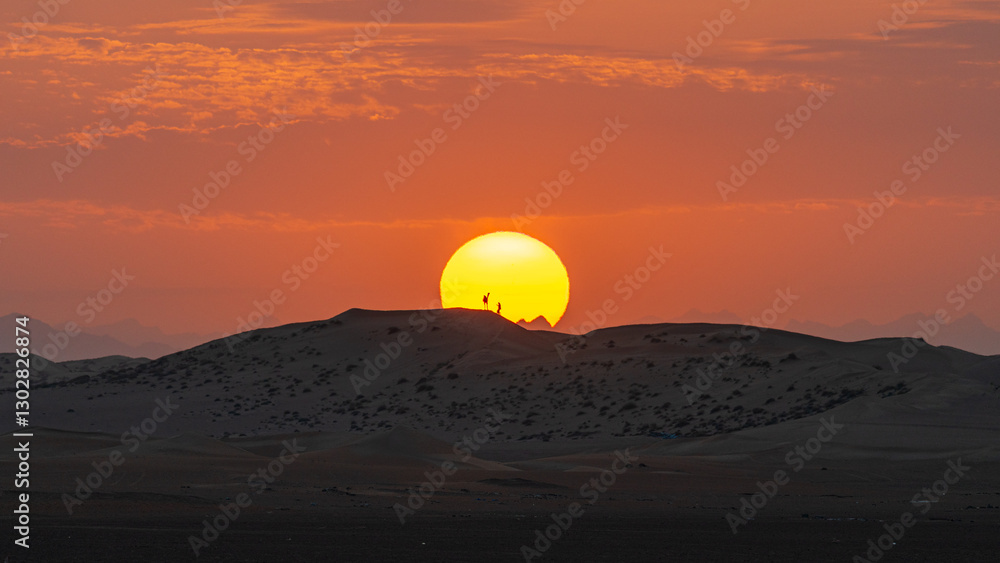 Fototapeta premium Camel and its handler on a sand dune framed in a sunrise