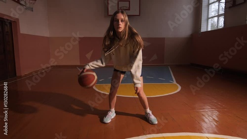 Young female basketball player dribbling in a gym