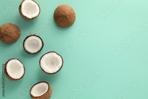 Halves of fresh coconuts on turquoise background, flat lay. Space for text