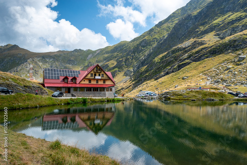 Bild auf Leinwand Panoramic view of Lake Balea with the reflection of the hotel and the Carpathian Mountains in the water in summer