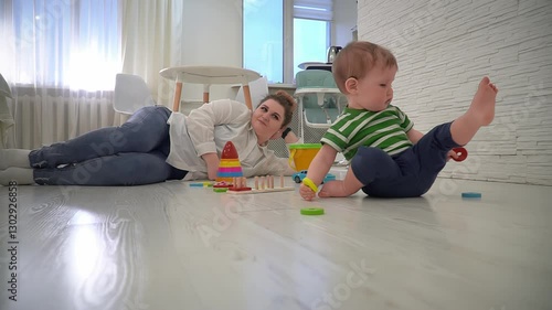 A little boy collects the colorful details of a wooden sorter. The baby loses his balance and falls to the floor.