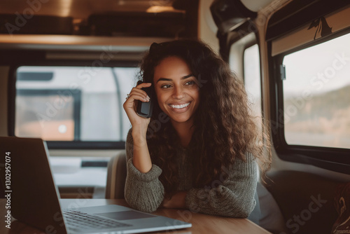 Young Woman Working Remotely Inside an RV  Smiling Digital Nomad Talking on Cell Phone  Cozy Motorhome Home Office Lifestyle  High-Resolution Stock Photo