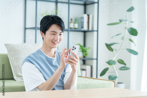 Fotografía リビングでスマホを使う若い男性