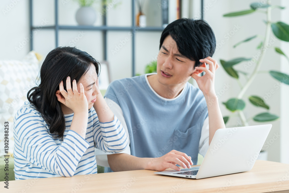 パソコンで悩む若い夫婦 パソコンで悩む若い夫婦