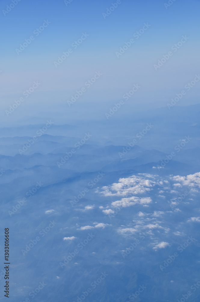 The view of the stunning landscape with mountains and clouds from the airplane window. Aerial view of the natural scene, mountain range. Travel and landscape scene. Travel and nature concept. The view of the stunning landscape with mountains and clouds from the airplane window. Aerial view of the natural scene, mountain range. Travel and landscape scene. Travel and nature concept.