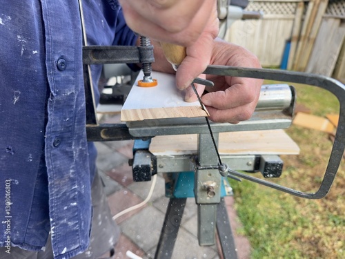 Photos Close up of a caucasian man's hands using a coping saw to cut the curved edge of