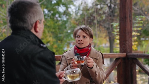 Lady explains principles of company operation to man partner sipping tea. Lady and man enjoy tea during business meeting of lady and man workers. Conversation between lady and man drinking tea in cafe photo