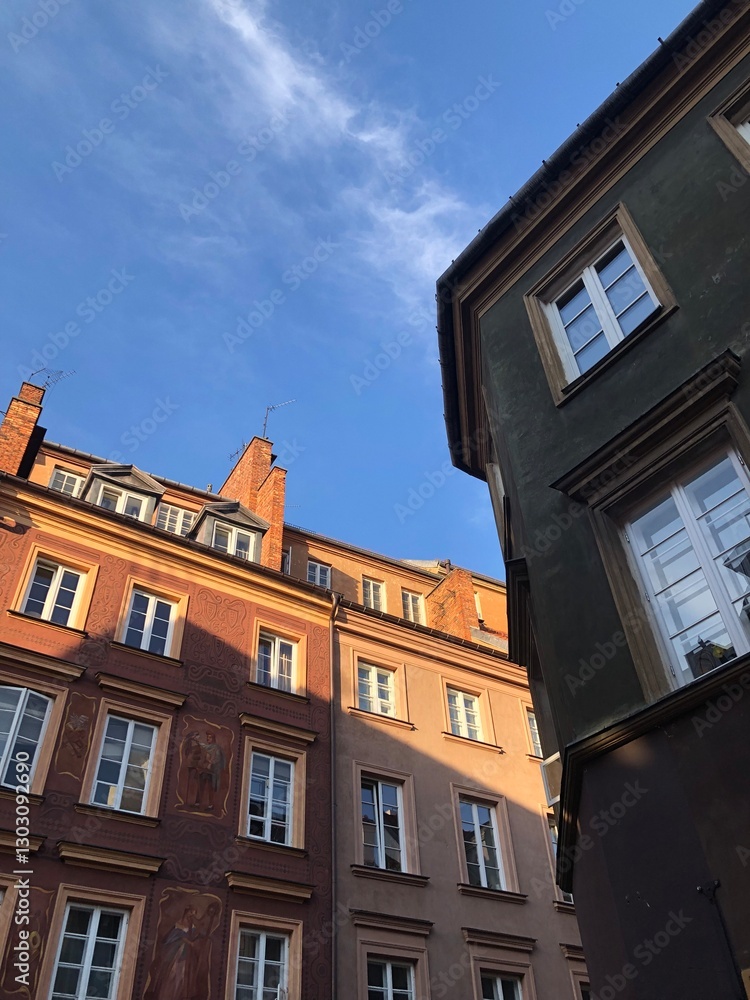 Fototapeta premium Charming European old town buildings bathed in warm golden-hour light. The colorful facades, intricate architectural details, and deep blue sky create a picturesque and inviting urban scene