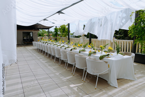 Elegant Outdoor Dining Setup with Floral Centerpieces and Draped Canopy