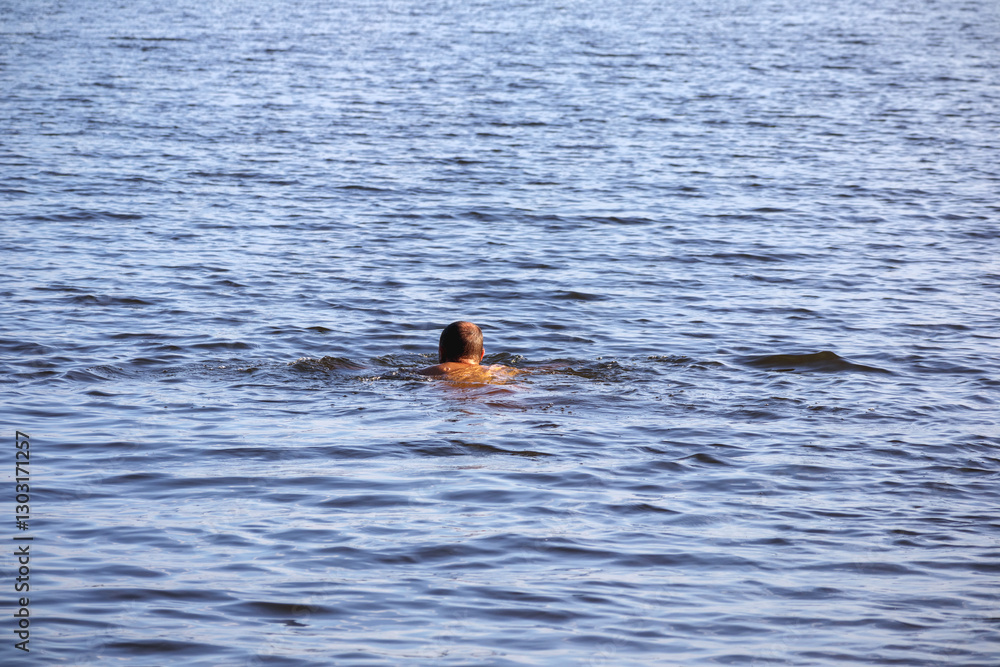 Fototapeta premium a man swimming in the water with his back to the viewer.
