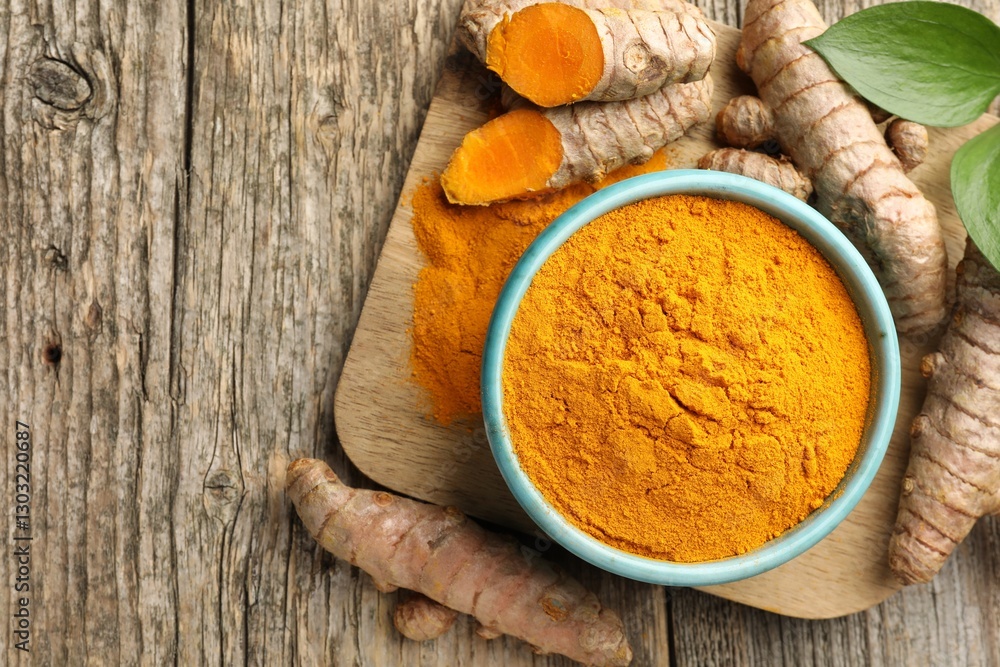 Turmeric powder in bowl, roots and leaves on wooden table, flat lay. Space for text Turmeric powder in bowl, roots and leaves on wooden table, flat lay. Space for text