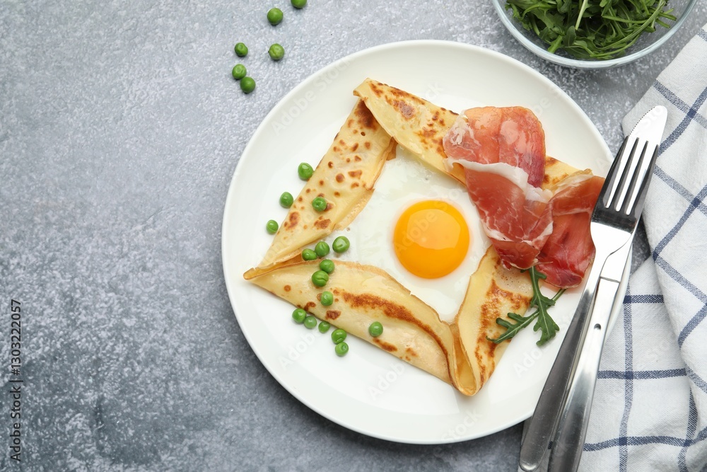 Delicious crepe with egg, bacon, arugula and green peas on grey table, flat lay. Space for text Delicious crepe with egg, bacon, arugula and green peas on grey table, flat lay. Space for text