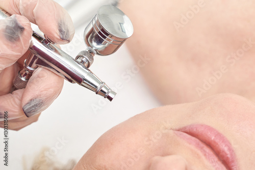 Fotografi Female adult receiving professional airbrush skin treatment with precision instrument close up