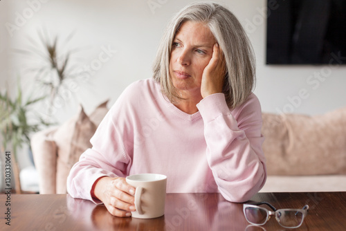 Fotografie Sad pensive middle age woman looking down depressed sitting on the sofa