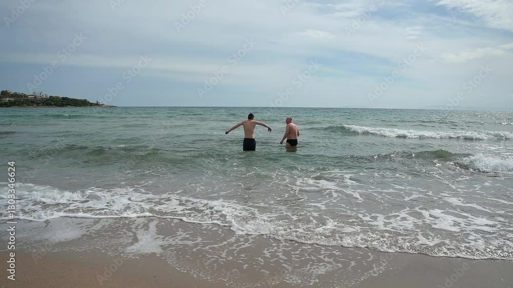 A father and son are swimming in the cold sea in winter A father and son are swimming in the cold sea in winter