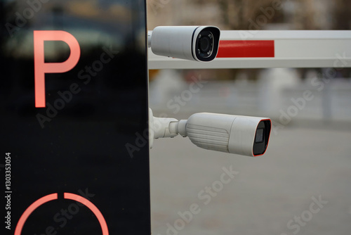 Obraz na płótnie Surveillance cameras mounted on parking entrance barrier for security monitoring and access control in an urban setting, selective focus. Automatic parking barrier closeup w salonie