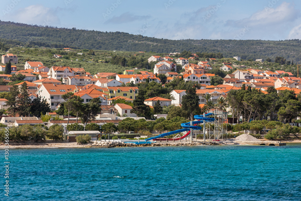 Fototapeta premium Supetar city in Brac island, Croatia. View from the sea. Picturesque scenic view on Supetar on Brac island, Croatia. Panoramic view on harbor of town Supetar from the side of sea. Brac, Croatia.