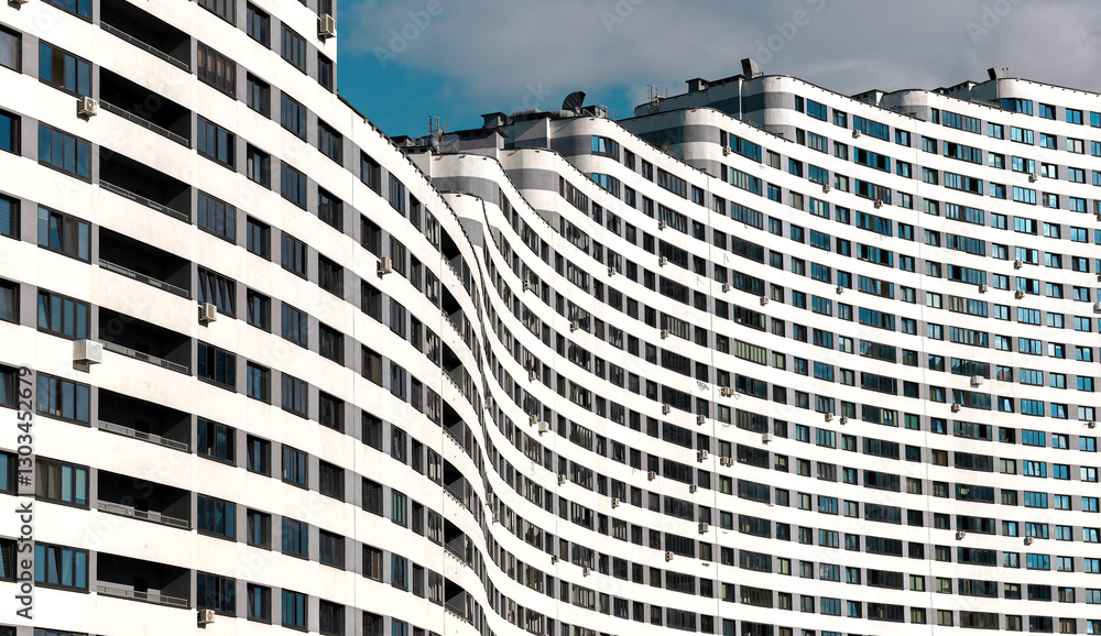 Fototapeta premium Modern high-rise condominium with a wavy, curved shape in a metropolitan city. Unique architecture, geometric design, concrete facade, and windows. New residential development offering accommodation,