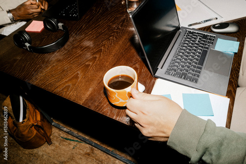 High angle view of male entrepreneur holding coffee cup near laptop on desk at office
