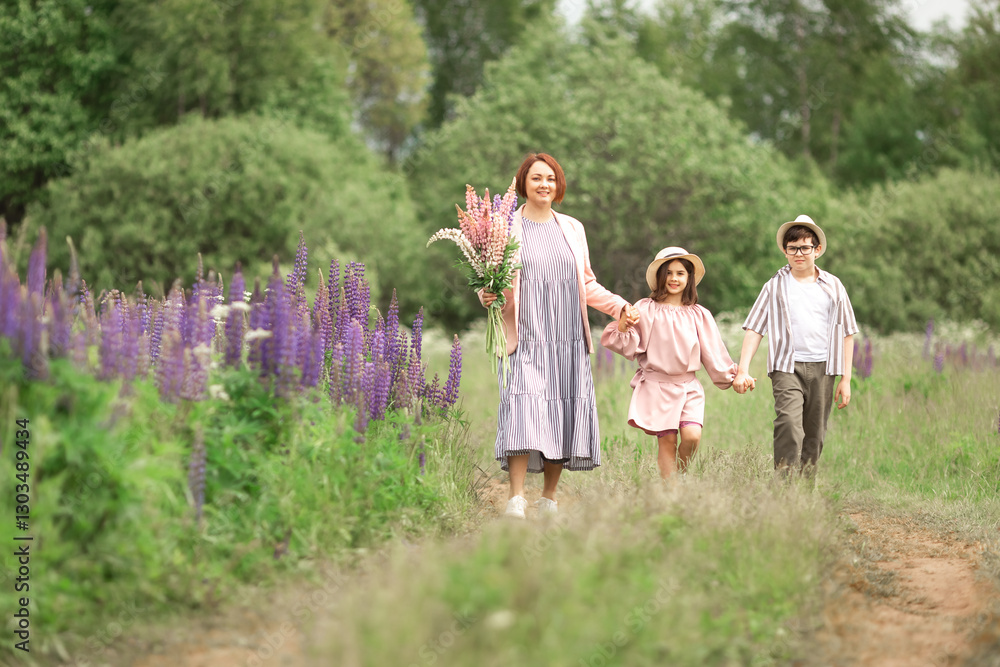 Fototapeta premium Caucasian young woman with children walking in lavender field holding flowers