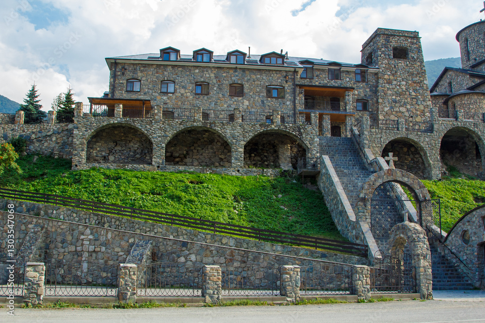 Fototapeta premium Majestic stone monastery sitting on a hillside with lush greenery and stone archways