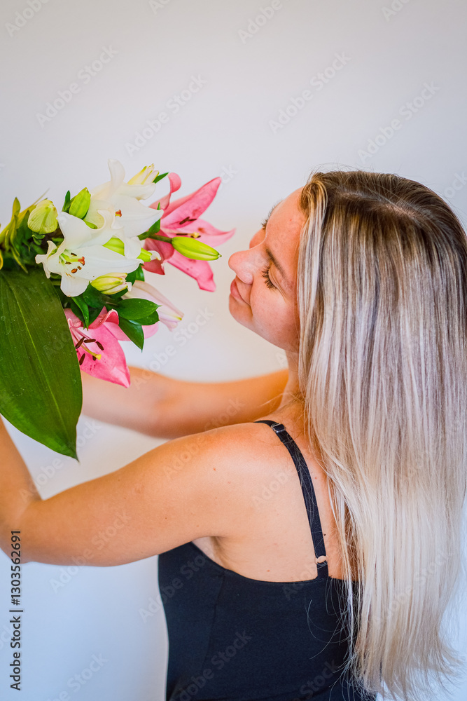 Naklejka premium A woman holding white and pink lilies against a white background.