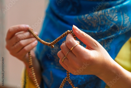 Muslim woman holding rosary and praying in mosque