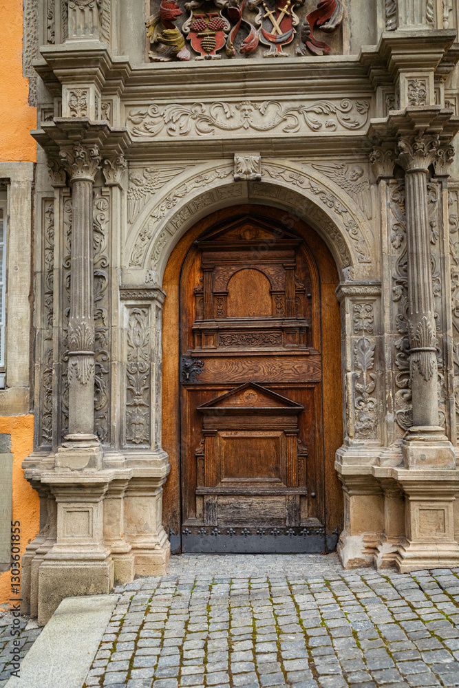 Ornate wooden door with stone archway and columns. Architectural detail, historical building. European architecture, cobblestone ground, decorative carving. Ornate wooden door with stone archway and columns. Architectural detail, historical building. European architecture, cobblestone ground, decorative carving.