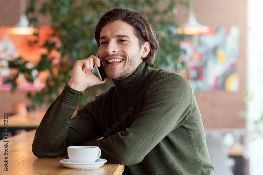 Good looking young man cheerfully talking on smartphone at lounge cafe, free space Good looking young man cheerfully talking on smartphone at lounge cafe, free space