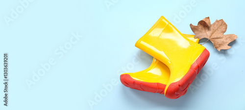 Schilderij op canvas Yellow gumboots with autumn leaf on blue background