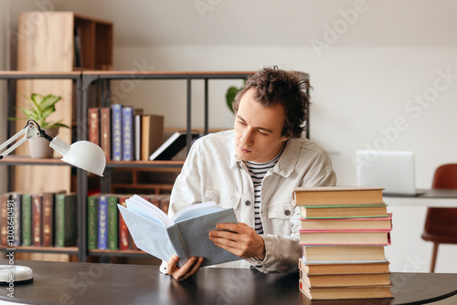 Young man reading book at table in library
